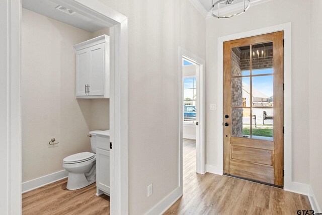 interior space with toilet, hardwood / wood-style flooring, a healthy amount of sunlight, and crown molding