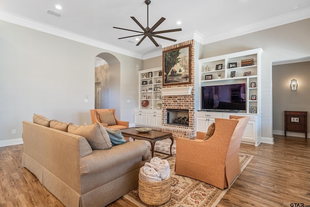 living room with a fireplace, ceiling fan, crown molding, and light hardwood / wood-style flooring