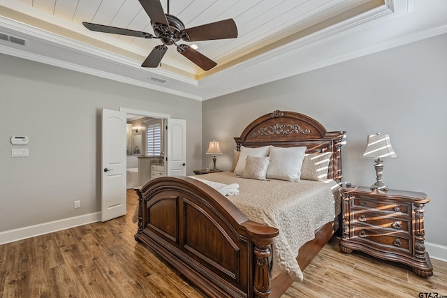 bedroom with ornamental molding, hardwood / wood-style floors, ceiling fan, and a tray ceiling