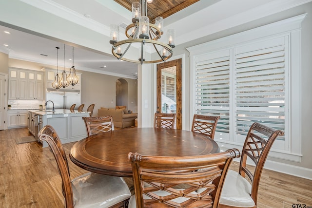 dining room featuring sink, a notable chandelier, light hardwood / wood-style floors, and crown molding