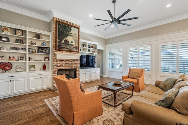 living room featuring hardwood / wood-style floors, ceiling fan, crown molding, and a brick fireplace