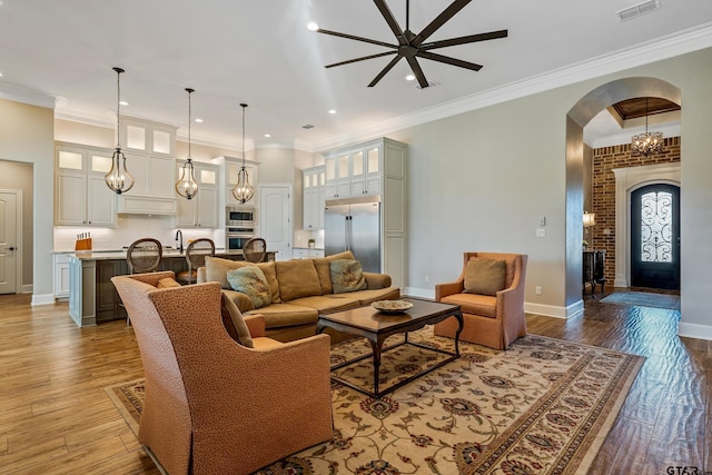 living room featuring light hardwood / wood-style floors, ceiling fan, and crown molding