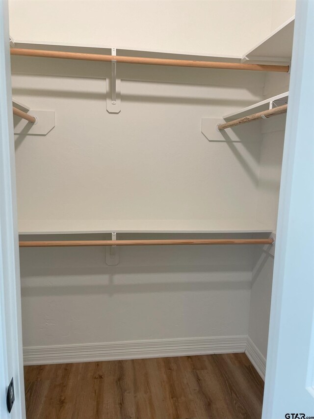 walk in closet with dark wood-type flooring