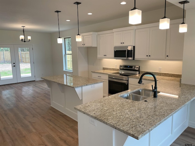 kitchen featuring appliances with stainless steel finishes, white cabinetry, hanging light fixtures, and sink