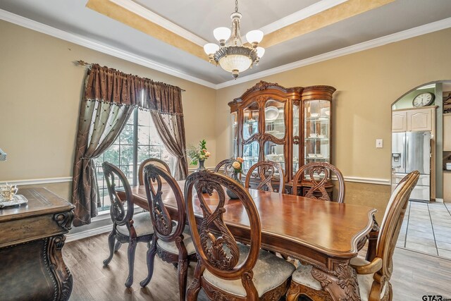18050 Deer Trl, Flint, TX 75762 - dining area featuring a raised ceiling, arched walkways, an inviting chandelier, crown molding, and light wood-style flooring
