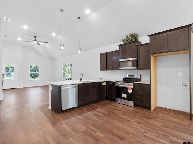 kitchen with dark wood-type flooring, stainless steel appliances, decorative light fixtures, sink, and kitchen peninsula