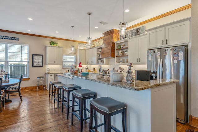 kitchen with dark stone counters, dark wood-type flooring, hanging light fixtures, and ornamental molding