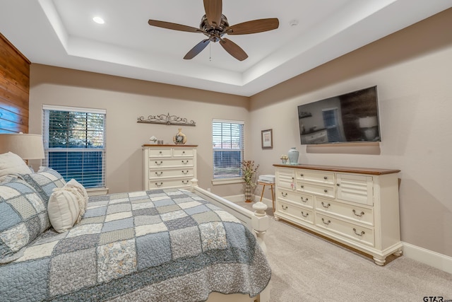 carpeted bedroom featuring multiple windows, a raised ceiling, and ceiling fan