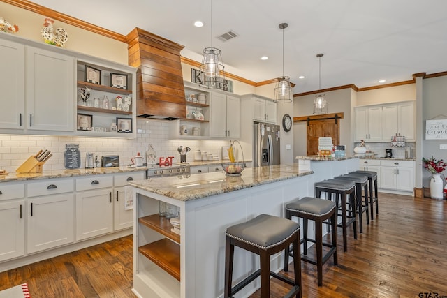 kitchen featuring dark hardwood / wood-style floors, a center island, light stone countertops, and stainless steel fridge with ice dispenser