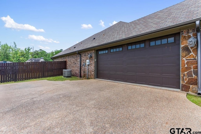 view of home's exterior featuring central AC, fence, brick siding, an attached garage, and aphalt driveway