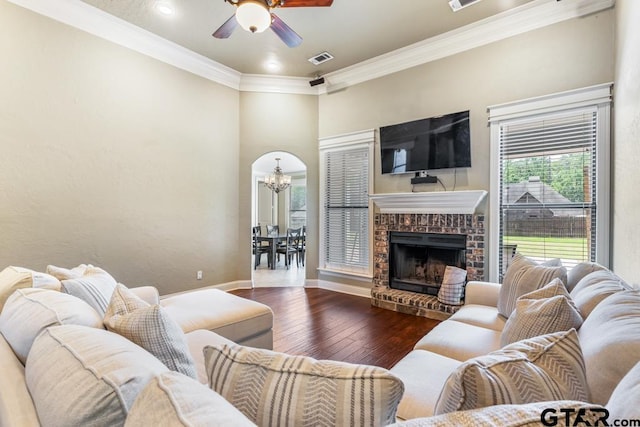living area featuring crown molding, hardwood / wood-style floors, ceiling fan with notable chandelier, baseboards, and visible vents