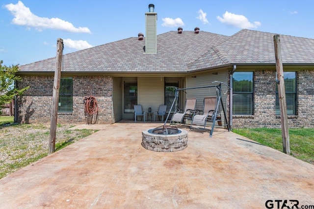 back of property featuring a fire pit, a chimney, brick siding, and a patio area