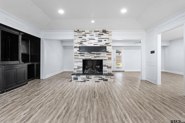 unfurnished living room featuring a stone fireplace, ceiling fan, lofted ceiling, and hardwood / wood-style flooring