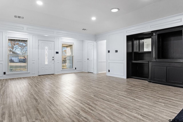 unfurnished living room with crown molding and light hardwood / wood-style flooring