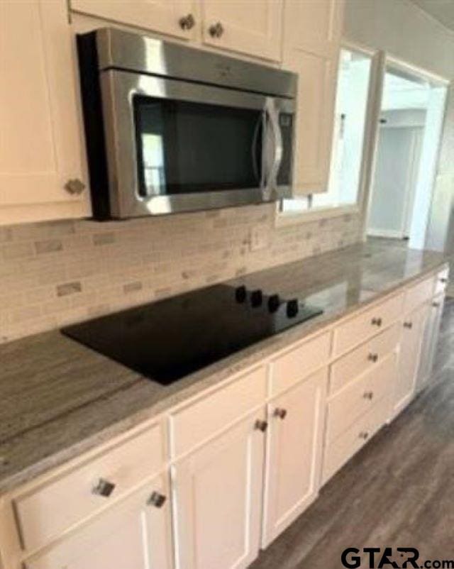 kitchen featuring black electric cooktop, light stone countertops, white cabinets, and dark hardwood / wood-style floors