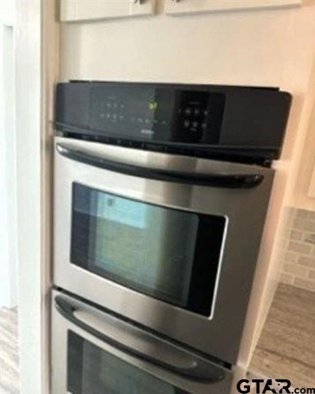 interior details with double oven and hardwood / wood-style flooring