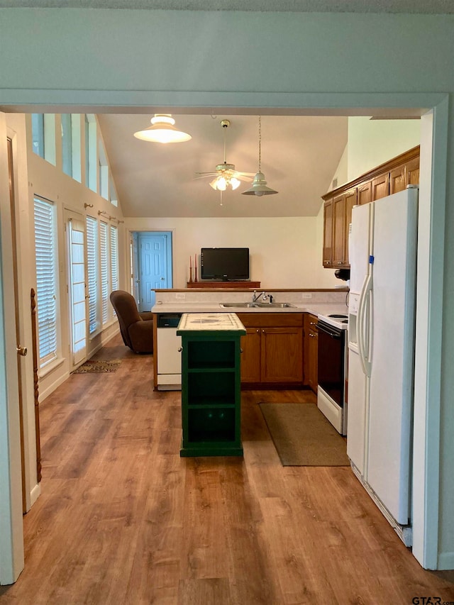 kitchen with lofted ceiling, white appliances, sink, and hardwood / wood-style flooring