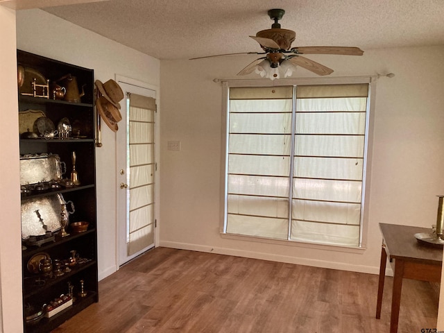 371 Wildwood Trl, Holly Lake Ranch, TX 75765 - unfurnished dining area with ceiling fan, wood finished floors, a textured ceiling, and baseboards