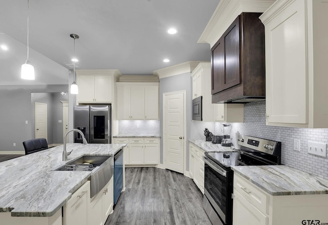 kitchen with stainless steel appliances, light wood-style flooring, a sink, backsplash, and an island with sink