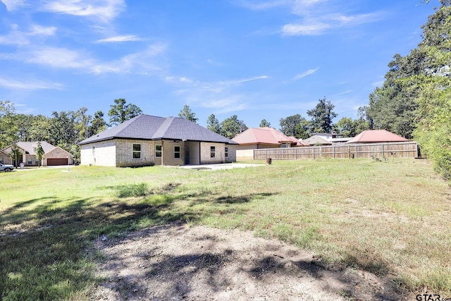 view of yard featuring fence, a detached garage, and a patio