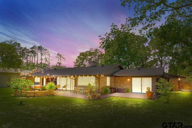 225 Texas Dr, Hideaway, TX 75771 - back of property at dusk with a yard, brick siding, and a chimney