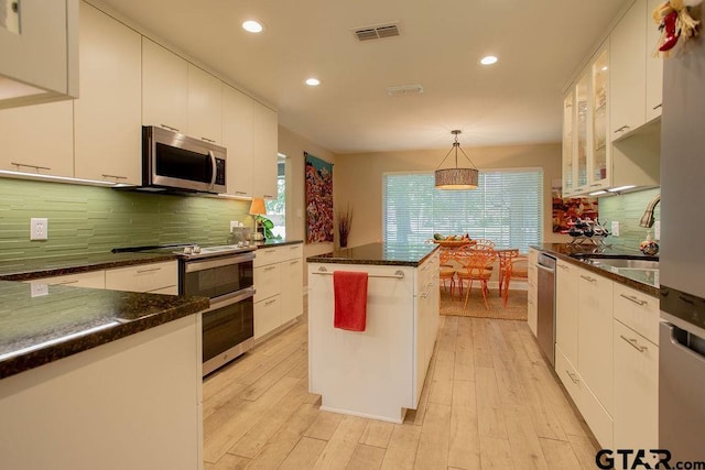 225 Texas Dr, Hideaway, TX 75771 - kitchen with appliances with stainless steel finishes, a sink, backsplash, decorative light fixtures, and white cabinetry