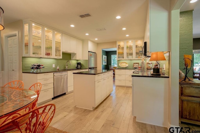 225 Texas Dr, Hideaway, TX 75771 - kitchen with appliances with stainless steel finishes, dark countertops, a center island, tasteful backsplash, and white cabinets