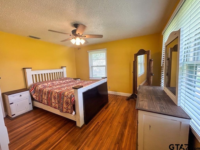 bedroom featuring ceiling fan, a textured ceiling, and dark hardwood / wood-style flooring