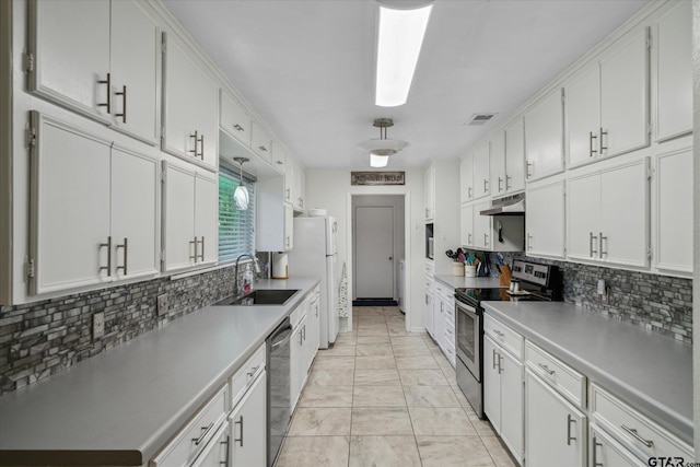 kitchen with white cabinets, stainless steel appliances, a sink, tasteful backsplash, and under cabinet range hood