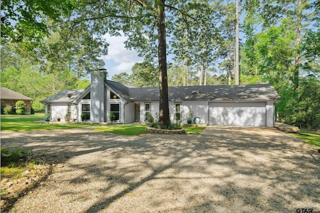 mid-century home with an attached garage, a front lawn, driveway, and a chimney