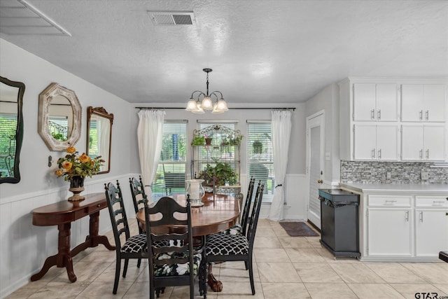 dining room featuring a notable chandelier, a wainscoted wall, light tile patterned flooring, and visible vents