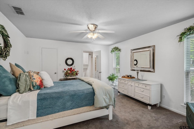 carpeted bedroom featuring baseboards, visible vents, connected bathroom, and ceiling fan