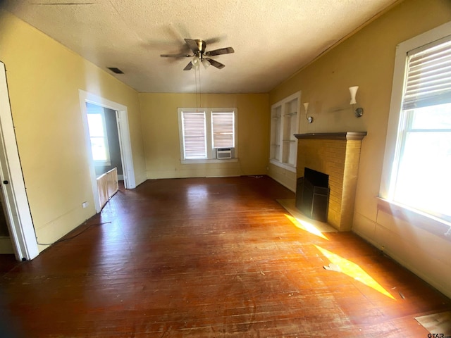 unfurnished living room featuring a brick fireplace, a textured ceiling, wood-type flooring, and ceiling fan