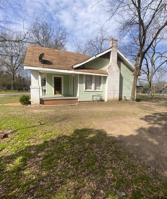 rear view of property featuring a porch and a yard