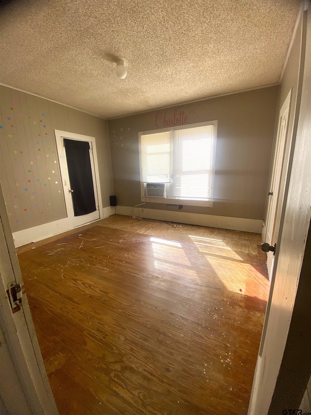 unfurnished bedroom featuring cooling unit, hardwood / wood-style flooring, and a textured ceiling