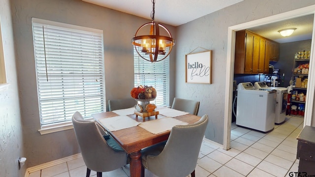 dining area with washing machine and clothes dryer, light tile patterned flooring, and a chandelier