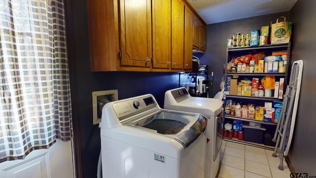 washroom with washing machine and clothes dryer, cabinets, a textured ceiling, and light tile patterned floors