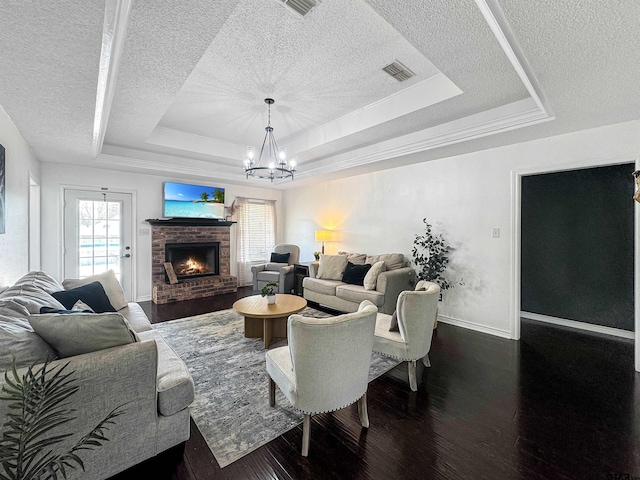 living room with visible vents, a textured ceiling, dark wood-type flooring, and a raised ceiling