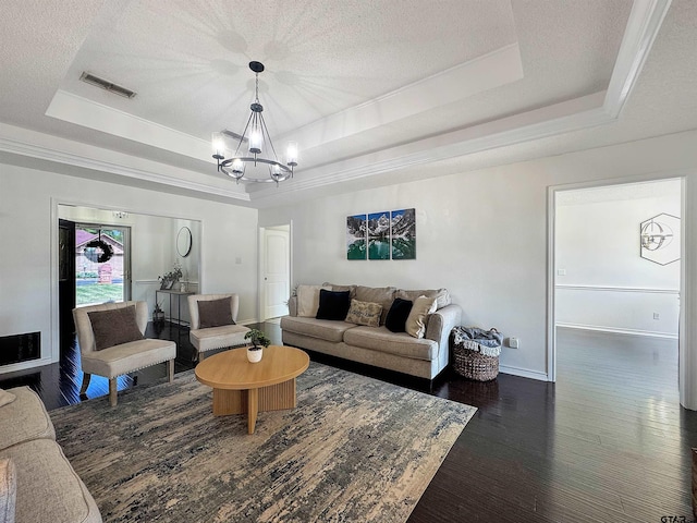 living room with visible vents, wood finished floors, a tray ceiling, and a notable chandelier