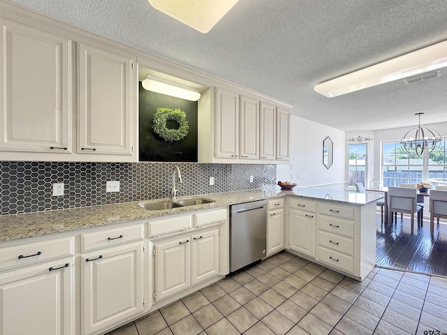 kitchen with stainless steel dishwasher, tasteful backsplash, a sink, a textured ceiling, and a peninsula