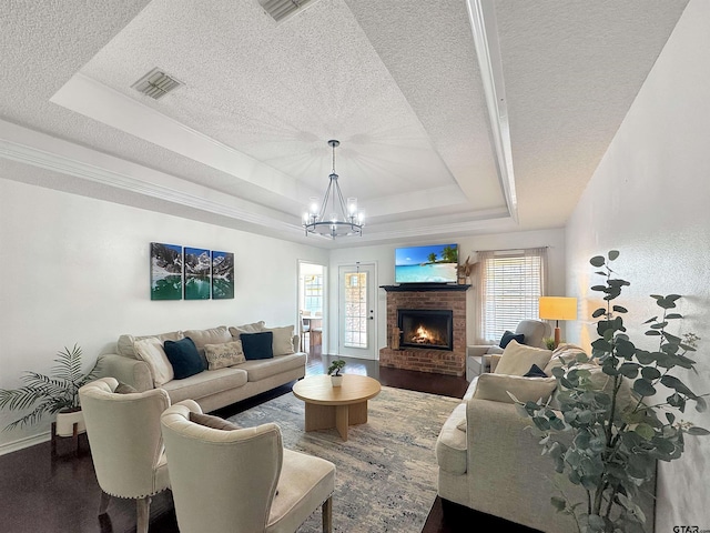 living area featuring an inviting chandelier, a tray ceiling, a textured ceiling, and plenty of natural light