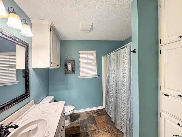 full bath with a textured ceiling, stone tile floors, vanity, baseboards, and toilet