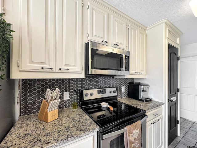 kitchen with light stone countertops, decorative backsplash, light tile patterned floors, and appliances with stainless steel finishes