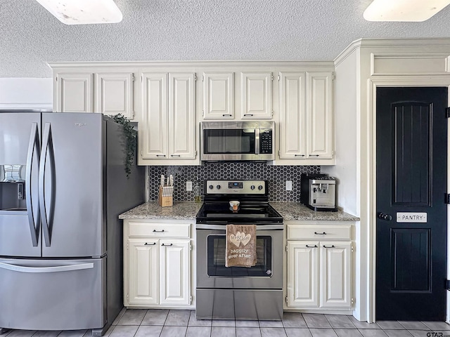 kitchen featuring stainless steel appliances, a textured ceiling, light stone counters, and light tile patterned flooring