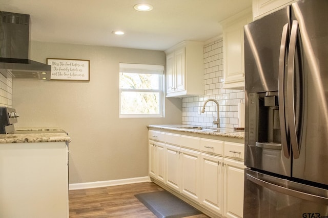 kitchen featuring ventilation hood, baseboards, a sink, stainless steel fridge, and backsplash