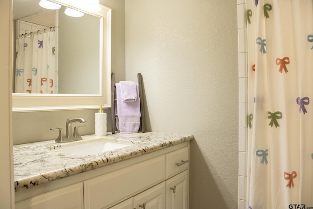 full bathroom featuring vanity, a shower with curtain, and a textured wall