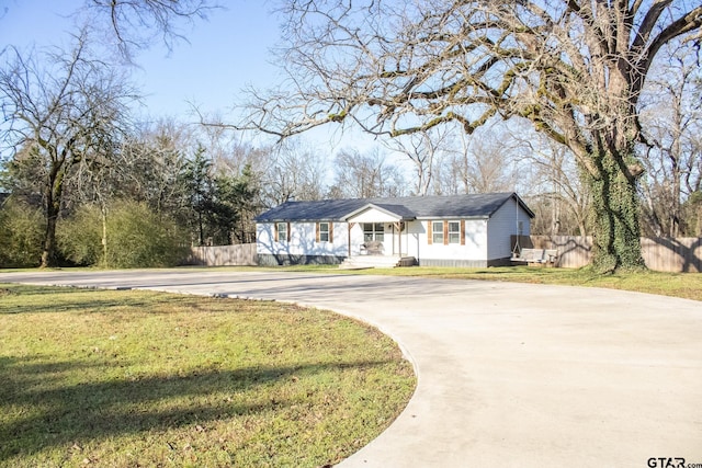 view of front of property featuring driveway, a front lawn, and fence