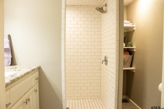 full bath featuring baseboards, vanity, a shower stall, and a textured wall