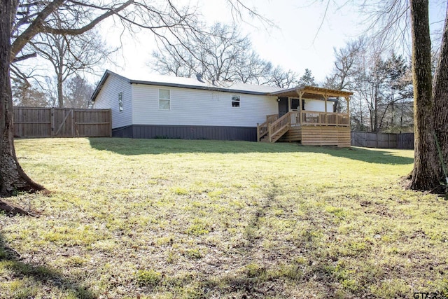 back of house with a deck, a gate, a fenced backyard, a yard, and stairway