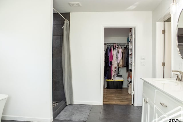 full bath featuring visible vents, a spacious closet, vanity, and a tile shower